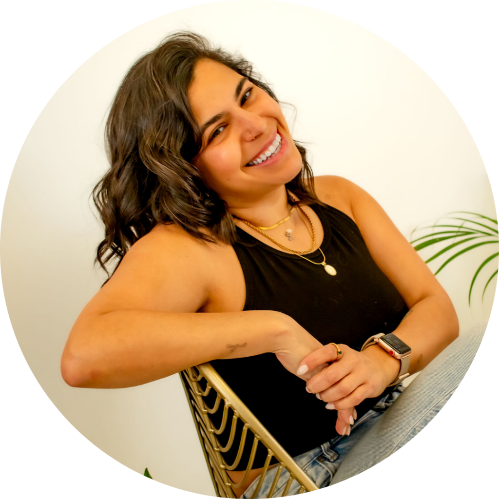 Mafe Salazar leans with one arm on the back of the chair, smiling