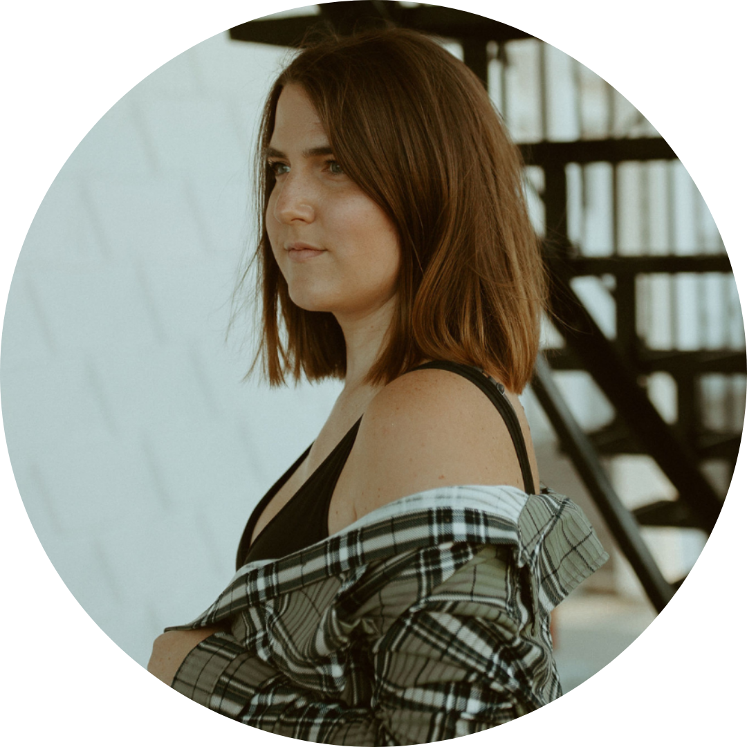 Steph Wharton stands looking to the left with a flannel hanging off her shoulder