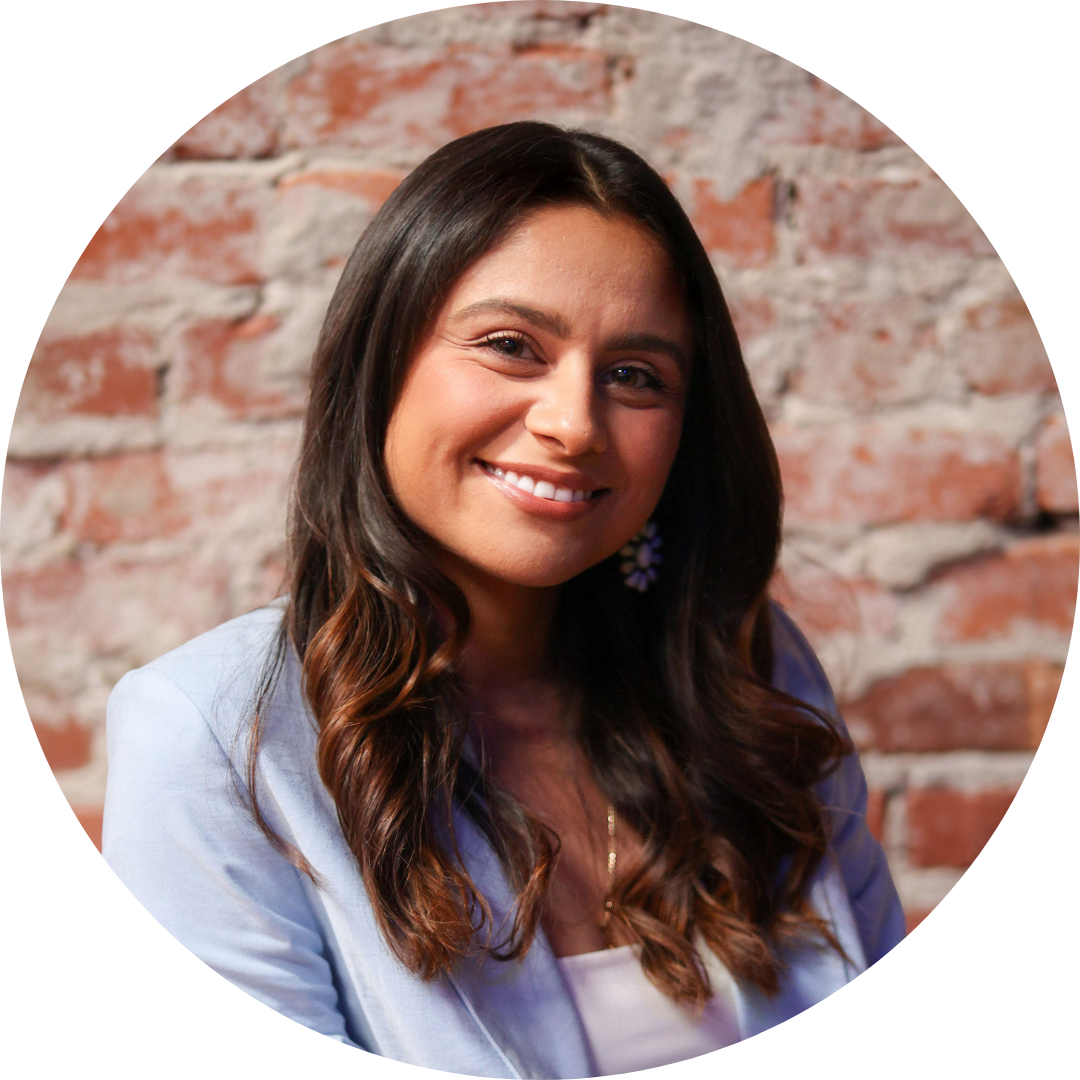 Yvonne Armenta against a brick wall smiles at the camera