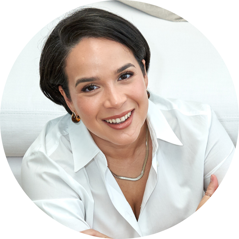 Heidy Caminero in a white shirt and silver necklace smiling at the camera