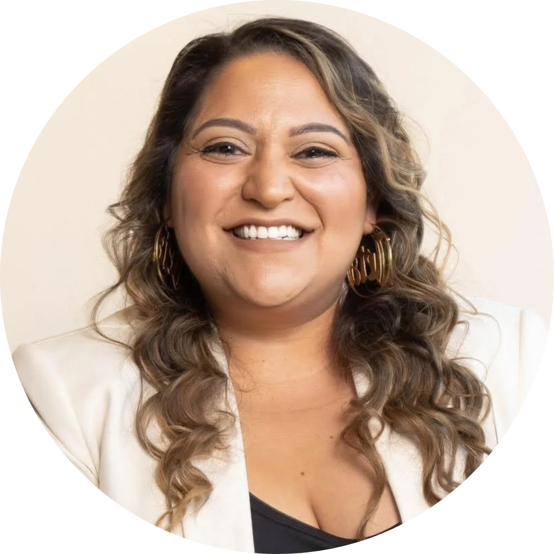 Kita Zuleta in a white blazer and dark top smiles at the camera